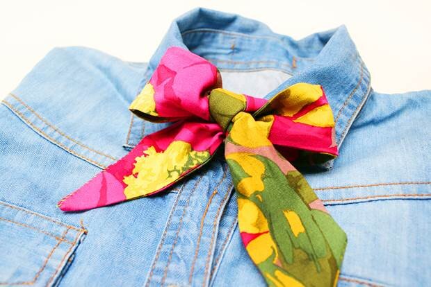A hand-sewn, floral print bowtie tied around the collar of a folded blue denim shirt.